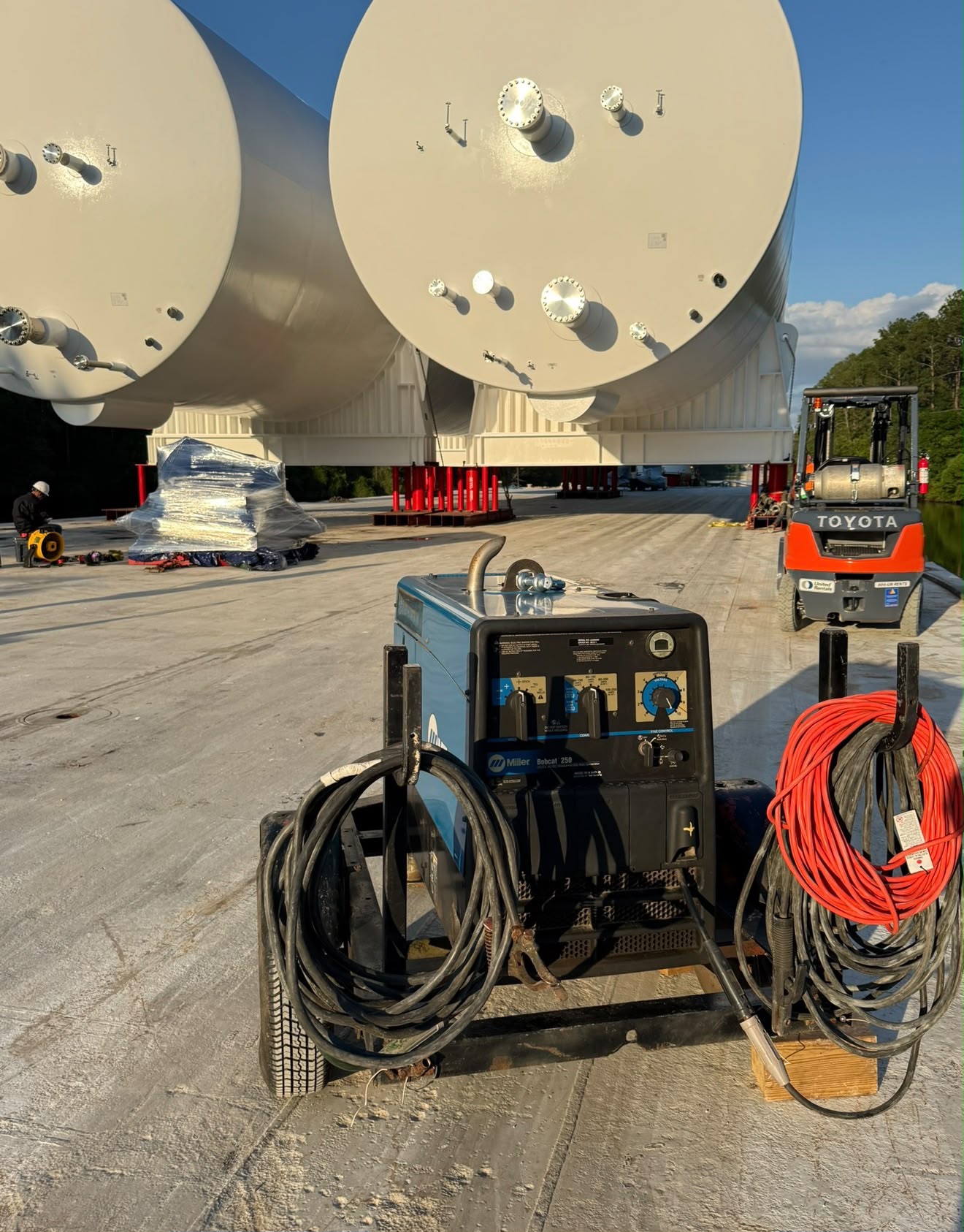 Welding equipment positioned beside large tanks